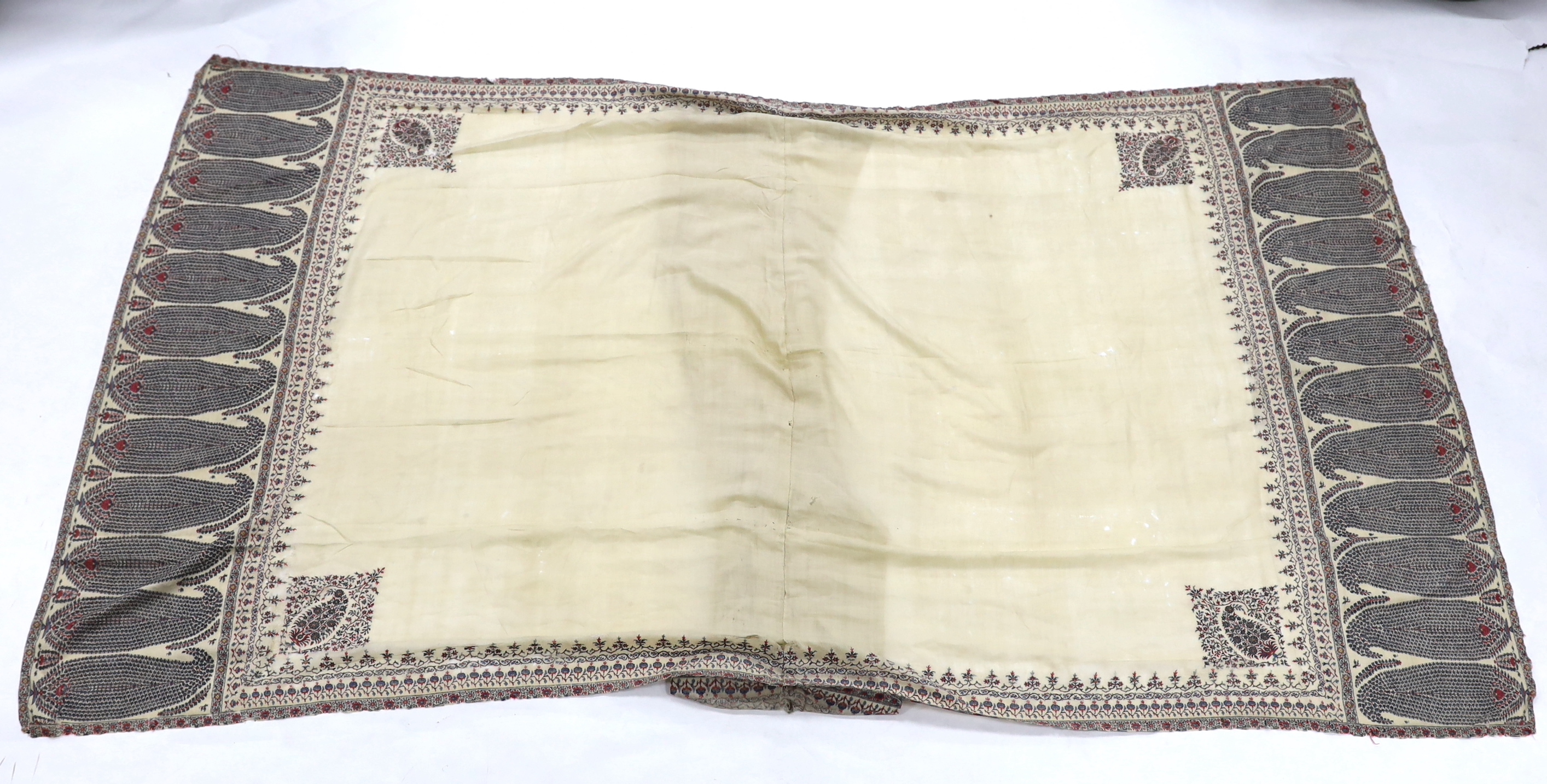 A 19th century fine cream woven Kashmiri shawl with blue and red teardrop design borders, an early 20th century gold satin pelmet with spot motifs of peacocks and flowers, 204cm long x 71cm high and a length of silk with